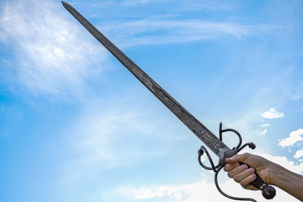 A hand holding a sword up to a blue sky